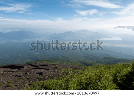 A breathtaking panoramic view from the summit of Mount Fuji, Japan's highest and most iconic volcano. The image captures the rugged volcanic crater, rocky ridges, winding hiking trails, and dramatic landscape above the clouds beneath a brilliant blue sky. This spectacular scene showcases the natural beauty and geological significance of Mount Fuji, a UNESCO World Heritage Site and one of Japan's most famous travel destinations. Ideal for themes of adventure, hiking, volcanic landscapes, nature, travel, and outdoor exploration.
