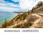 Breathtaking photo of Sleeping Bear Dunes along Lake Michigan on a sunny summer day. The sweeping sandy dunes and lush shoreline represent the natural beauty and adventure of Northern Michigan.