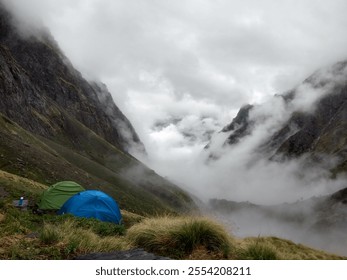 A breathtaking scene of mist laden mountains with our tents pitched amidst lush greenery. The clouds caresses the towering cliffs. Perfect for showcasing travel and allure of great outdoors. - Powered by Shutterstock