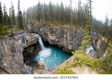 A breathtaking scene of a powerful waterfall plunging into a deep, turquoise pool surrounded by towering cliffs and dense forest. - Powered by Shutterstock