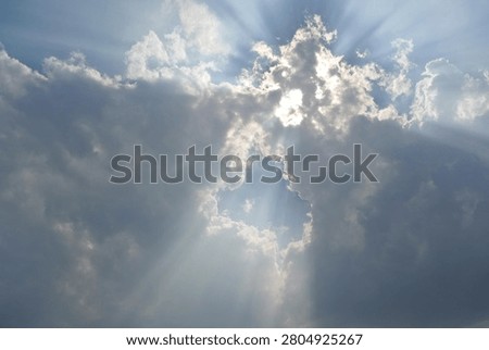 A breathtaking shot of dramatic sunbeams breaking through dramatic gray clouds in a blue sky. Beautiful natural crepuscular rays or God's rays effect beaming through cloud gap, perfect for spiritual, hope, and inspirational concepts.