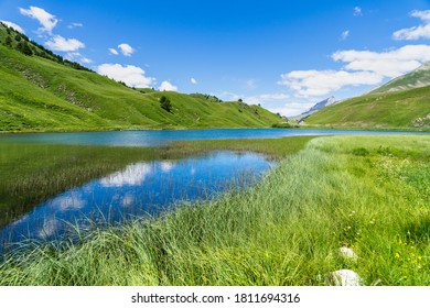 A Breathtaking Shot Of A Green Field And Lake In Maddalena Pass, Italy