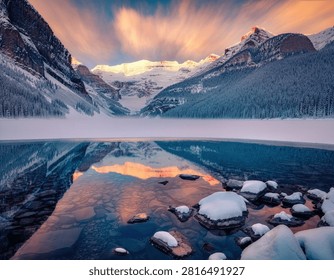 A breathtaking snowy alpine reflection featuring majestic snow-capped mountains mirrored perfectly in a crystal-clear alpine lake beneath a vibrant blue sky. Warm golden sunrise light illuminates the rugged peaks while the calm water creates a flawless reflection, enhancing the peaceful beauty of the untouched wilderness. Surrounded by pristine evergreen forests and fresh mountain air, this stunning high-resolution landscape is ideal for travel, tourism, adventure, environmental, wellness, and commercial design projects.