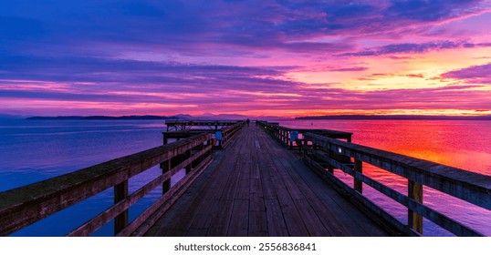 A breathtaking sunrise paints the sky with vibrant colors over Sidney Pier on Vancouver Island, BC. The wooden pier stretches into calm waters, creating a peaceful and serene atmosphere. - Powered by Shutterstock