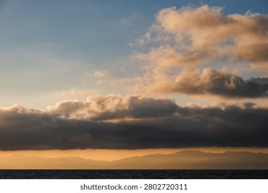 Breathtaking sunset over the ocean with dramatic clouds and distant mountains