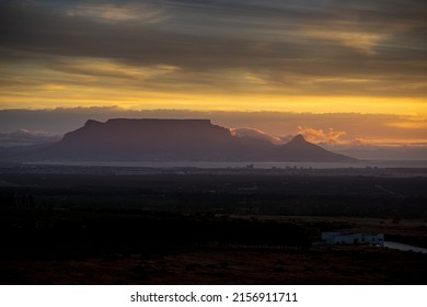 A Breathtaking Sunset With Silhouette Of A Mesa Under A Cloudy Sky