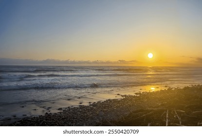 A breathtaking sunset view of the Pacific Ocean in El Tunco, El Salvador, featuring warm golden light reflecting on gentle waves as they roll onto a rocky shoreline.
 - Powered by Shutterstock