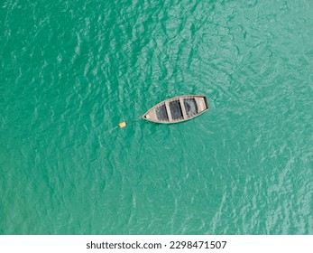 A breathtaking top view of a serene blue-green lake with a wooden boat gently floating on its surface. - Powered by Shutterstock