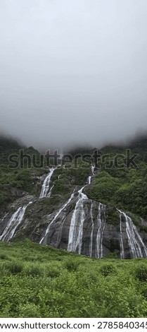 Breathtaking vertical view of a multi-stream waterfall flowing through lush green forest and dark rocks in the misty mountains of Anini, Dibang Valley, Arunachal Pradesh. One of Northeast India's most remote and unexplored natural wonders, captured during monsoon season. Perfect for travel, nature, adventure and climate concepts.
