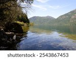 Breathtaking view of Cameron Lake with blue-green waters, surrounded by majestic mountains and a clear blue sky, Vancouver Island, BC