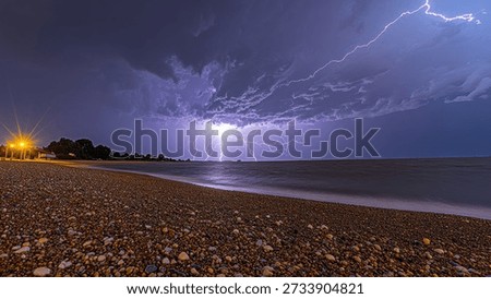 Breathtaking view of a dramatic lightning storm occurring over a pebble beach at night. The powerful lightning illuminates the dark clouds against the horizon, creating a striking contrast with the tranquil waters of the sea and the textured pebble beach.