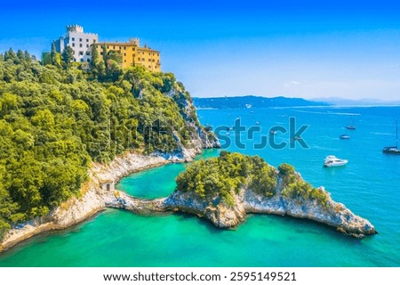 A breathtaking view of Duino Castle near Trieste, Italy, featuring its dramatic cliffside position overlooking the Adriatic Sea while rugged coastline create a perfect contrast to the historic charm 
