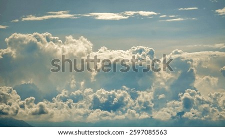 Breathtaking view of fluffy clouds against a clear blue sky, conveying peace and tranquility. Ideal for nature, weather, or inspirational themes.