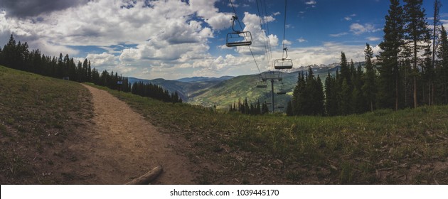 Breathtaking View Of A Hiking Trail, Coniferous Trees, An Idle Ski Lift In Summer Atop Vail Mountain, With A Panorama Of The Rocky Mountains In The Backdrop, Vail, Colorado