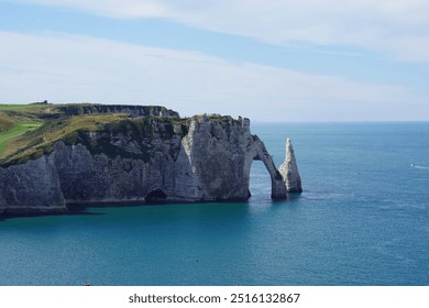 A breathtaking view of a large coastal rock formation with a natural arch and a pinnacle rising from the turquoise waters of the sea - Powered by Shutterstock