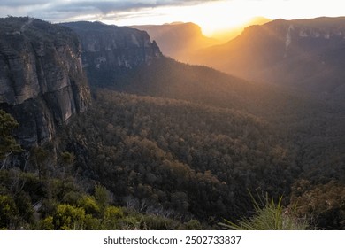 Breathtaking view of majestic mountains under a cloudy sky, lush greenery, and trees illuminated by a stunning sunrise in Sydney, Australia. Perfect for nature and landscape enthusiasts. - Powered by Shutterstock