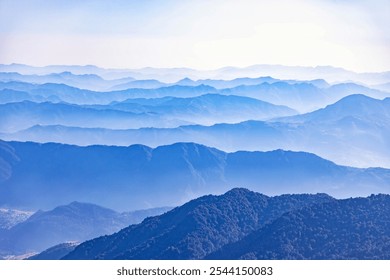 A breathtaking view of misty mountain ranges, with layers of lush green peaks fading into the fog. The serene landscape captures the natural beauty and tranquility of the distant, rolling hills. - Powered by Shutterstock