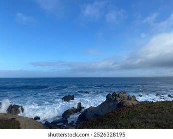 A breathtaking view of the Monterey coast, where rugged cliffs meet the crashing Pacific waves. The rocky shoreline contrasts with the deep blue ocean, which stretches endlessly toward the horizon.  - Powered by Shutterstock