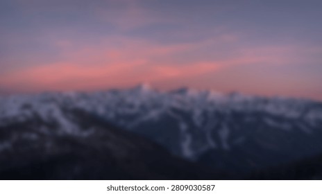 A breathtaking view of a mountain range bathed in the warm glow of sunrise, with soft clouds and a colorful sky.