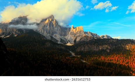A breathtaking view of a mountain range with dramatic clouds and vibrant autumn foliage.