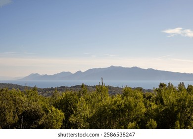 A breathtaking view of a mountain range overlooking a lush green landscape, capturing the beauty of nature and the tranquility of rural vistas under clear blue skies.