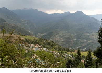 A breathtaking view of a mountain valley with scattered settlements, lush greenery and terraced fields. Snow-capped peaks rise in the distance under an overcast sky, creating a serene landscape. - Powered by Shutterstock