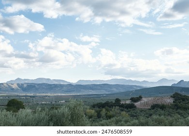 Breathtaking view of a mountainous landscape under a partially cloudy sky, with rolling hills and lush vegetation in the foreground. - Powered by Shutterstock