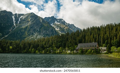 A breathtaking view of Popradské Pleso lake, surrounded by a dense coniferous forest and majestic snow-capped peaks. Featuring the charming Mountain Hotel Popradské Pleso, perfect for nature lovers an - Powered by Shutterstock