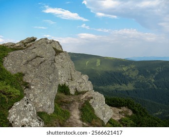 A breathtaking view of a rocky formation overlooking a lush green valley and distant mountains under a partly cloudy sky. Natures beauty is evident in every detail of the landscape. - Powered by Shutterstock