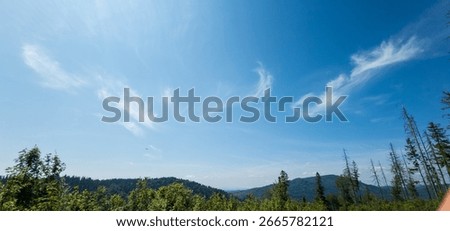 A breathtaking view of rolling mountains under a clear blue sky with wispy clouds, ideal for travel promotions, outdoor brands, or nature-inspired ads