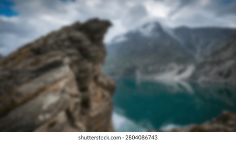 A breathtaking view of a rugged mountain range overlooking a vibrant turquoise lake, with a prominent rocky outcrop in the foreground.