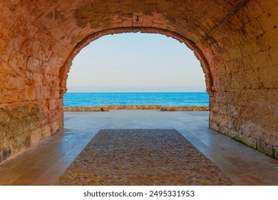 Breathtaking view of the sea seen through an ancient stone archway in Tarragona. - Powered by Shutterstock