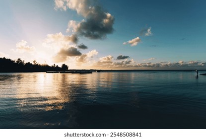 A breathtaking view of a serene coastal sunset with golden hues reflecting on calm waters. The silhouetted trees and boats add depth to the tranquil atmosphere of Mauritius. - Powered by Shutterstock