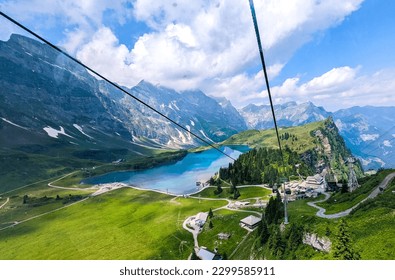 Breathtaking view of a serene lake nestled atop Mount Titlis. The lake itself is calm and tranquil, with clear, still waters that reflect the surrounding mountains and sky.