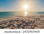 Breathtaking view of a serene sunset reflecting on the tranquil Jordanian waters of the Dead Sea in Jordan, with salt formations