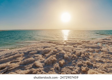Breathtaking view of a serene sunset reflecting on the tranquil Jordanian waters of the Dead Sea in Jordan, with salt formations - Powered by Shutterstock