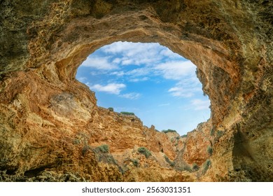 A breathtaking view of the skylight in Benagil Cave, showcasing the natural rock formations and the blue sky above. This famous sea cave is known for its unique beauty. Algarve, Portugal. - Powered by Shutterstock