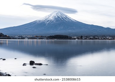 A breathtaking view of a snow-capped mountain reflecting on calm water, surrounded by a tranquil landscape. Ideal for nature lovers and travel enthusiasts. - Powered by Shutterstock