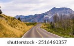 Breathtaking view of a straight road leading through Waterton, Alberta. Majestic mountains and open sky create a sense of adventure and tranquility in the Canadian landscape.