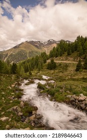 A Breathtaking View Of Stream Flowing Through Lush Green Vegetation In The Valley