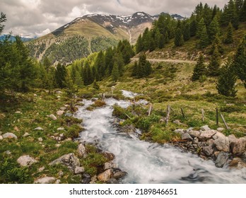 A Breathtaking View Of Stream Flowing Through Lush Green Vegetation In The Valley