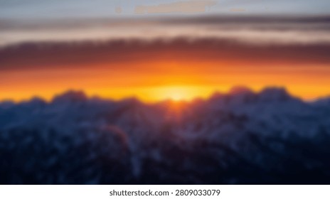 A breathtaking view of a sunset casting a warm golden glow over a majestic mountain range, with clouds adding depth and drama to the scene.