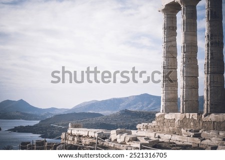 A breathtaking view of the Temple of Poseidon in Sounio, near Athens, featuring its iconic ancient columns. Behind the temple, the stunning landscape of Attica unfolds, blending history and nature.