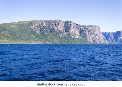 Breathtaking view of towering rocky cliffs overlooking a deep blue sea under a clear sky, capturing the essence of natural beauty and tranquility. - Powered by Shutterstock