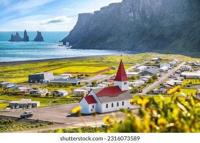 Breathtaking view of Vikurkirkja christian church in blooming flowers. Most popular tourist destination. Location: Vik village in Myrdal Valley, Iceland, Europe.