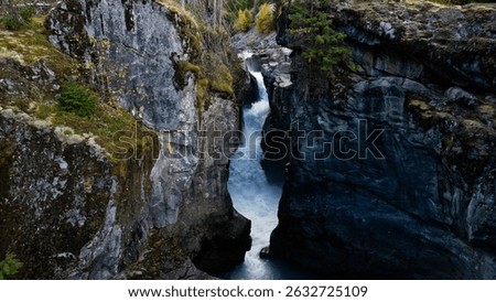 A breathtaking view of a waterfall in Nairn Falls Provincial Park, Canada, surrounded by rocky mountains and evergreen forest