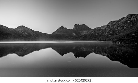 Breathtaking views of Mountain Cradlle National Park in Tasmania. Early morning smoke on water unfolds a mirror reflection of Cradle Mountain peaks in peaceful still waters of ake Dove.