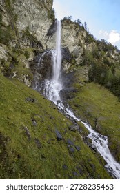 A breathtaking waterfall tumbles dramatically from steep cliffs in the Grossglockner region of Austria. Surrounded by lush greenery and rugged terrain, the water flows with great force, creating a mesmerizing sight against the backdrop of towering mountains. The sound of rushing water fills the air, while the mist rising from the base adds to the enchantment of the location.