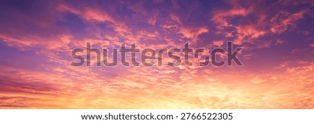 A breathtaking wide-angle panoramic view of a dramatic sunset sky. The atmosphere is filled with scattered altocumulus clouds illuminated by a vibrant gradient of fiery orange, deep pink, and majestic purple tones. The golden light radiates from the horizon, creating a high-contrast and cinematic background. This natural scene captures the essence of the golden hour, perfect for inspirational backdrops, website banners, and cinematic nature projects. The image conveys a sense of wonder, peace, and the vastness of the twilight sky.