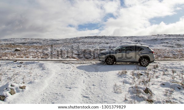 Brecon Beacons, UK: January 30, 2019: A\
Lexus NX 300h F-Sport crossover hybrid car on the road side in snow\
and dangerous icy conditions with copy\
space.